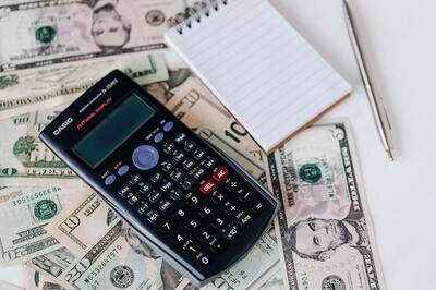 calculator notebook and dollar bills